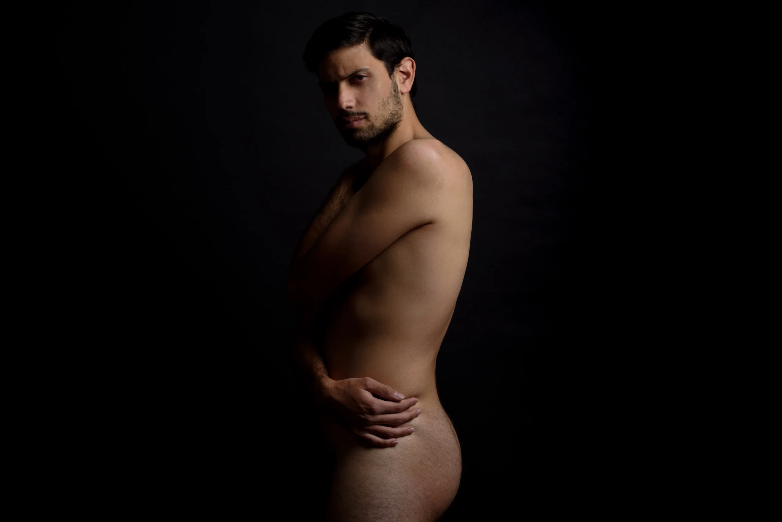 Un homme qui s'enlace en regardant le photographe
