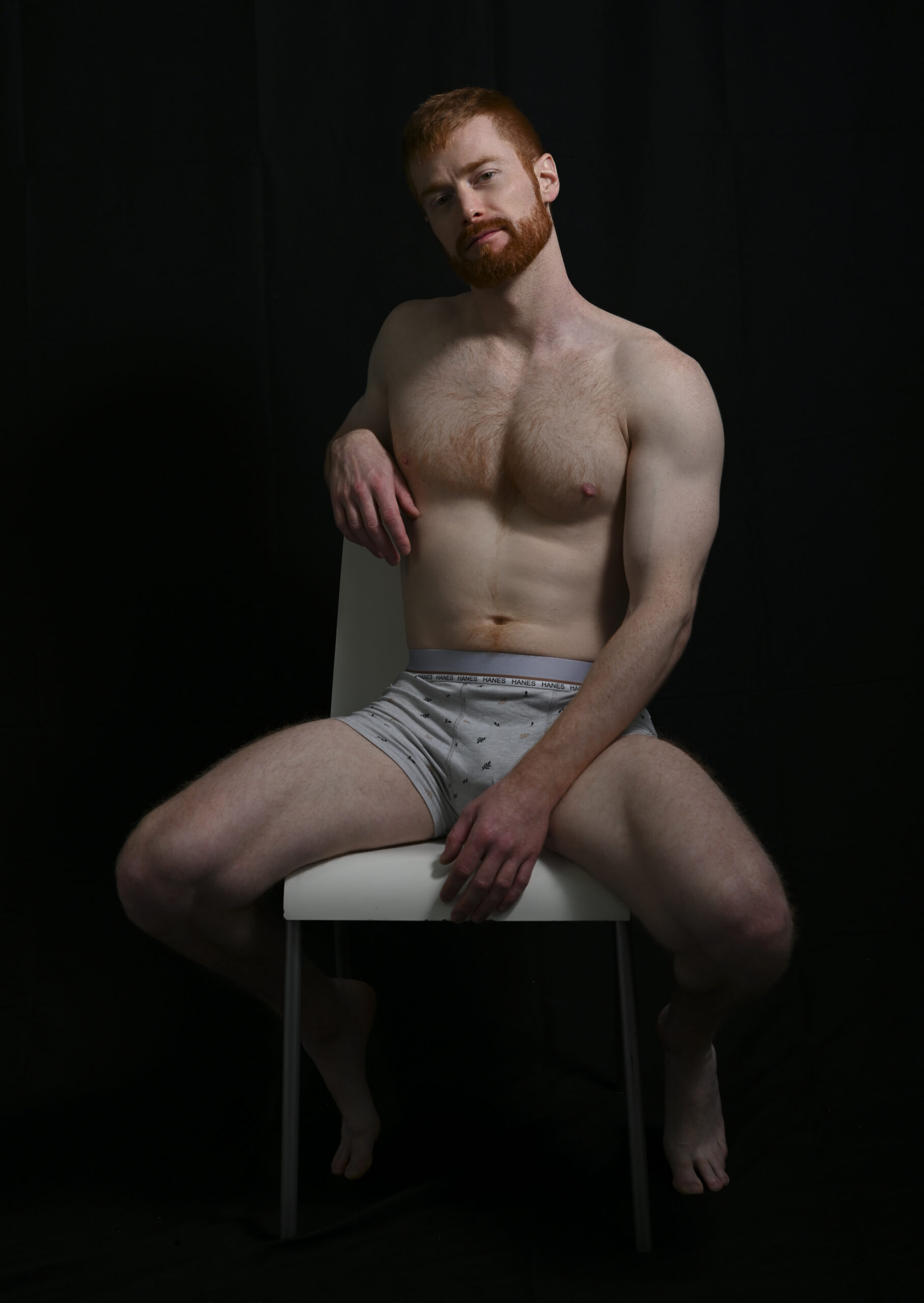 Homme musclé et roux en boxer assis sur une chaise