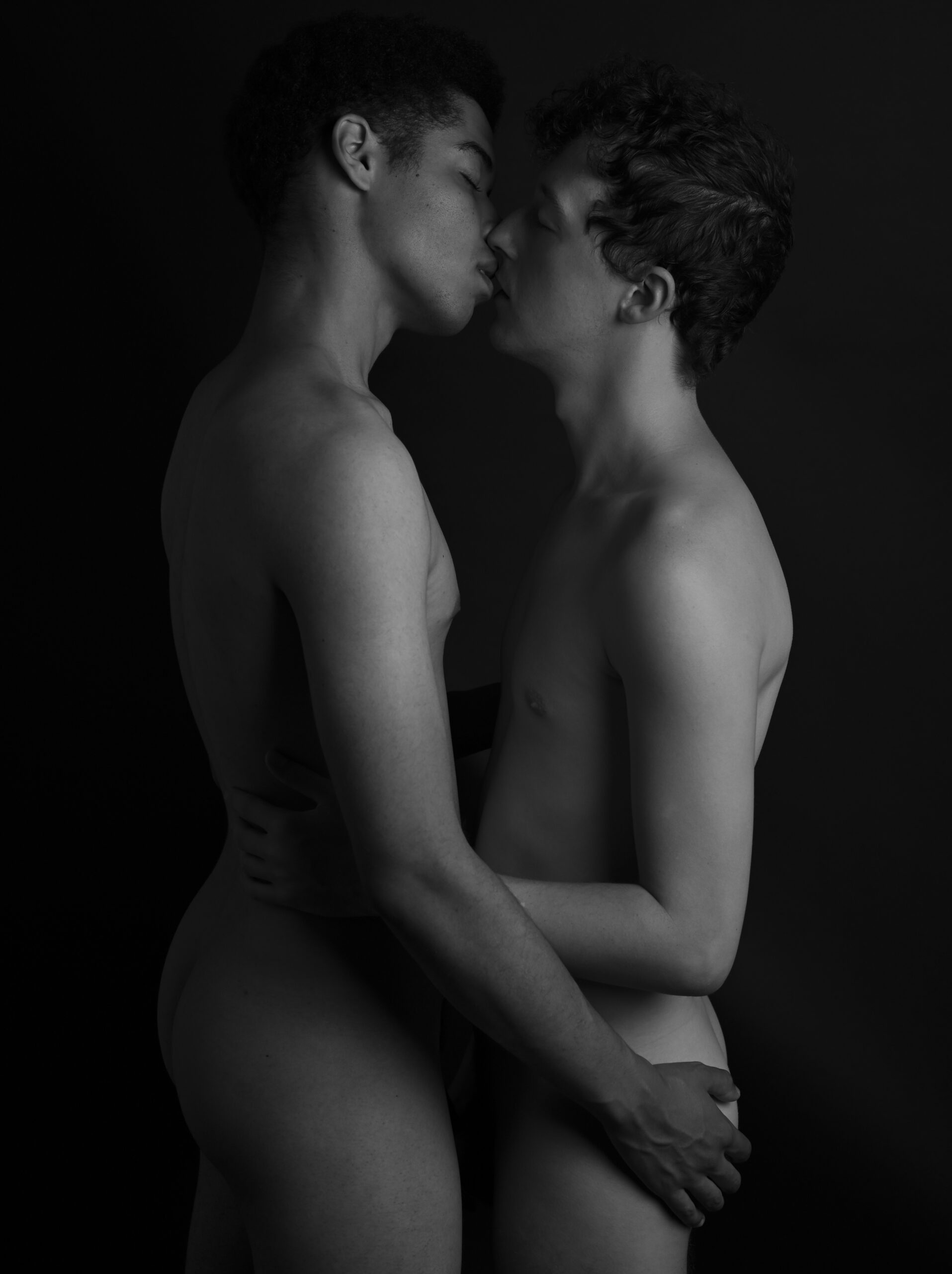Photo en noir et blanc de deux hommes qui se caressent sensuellement en se préparant à s'embrasser