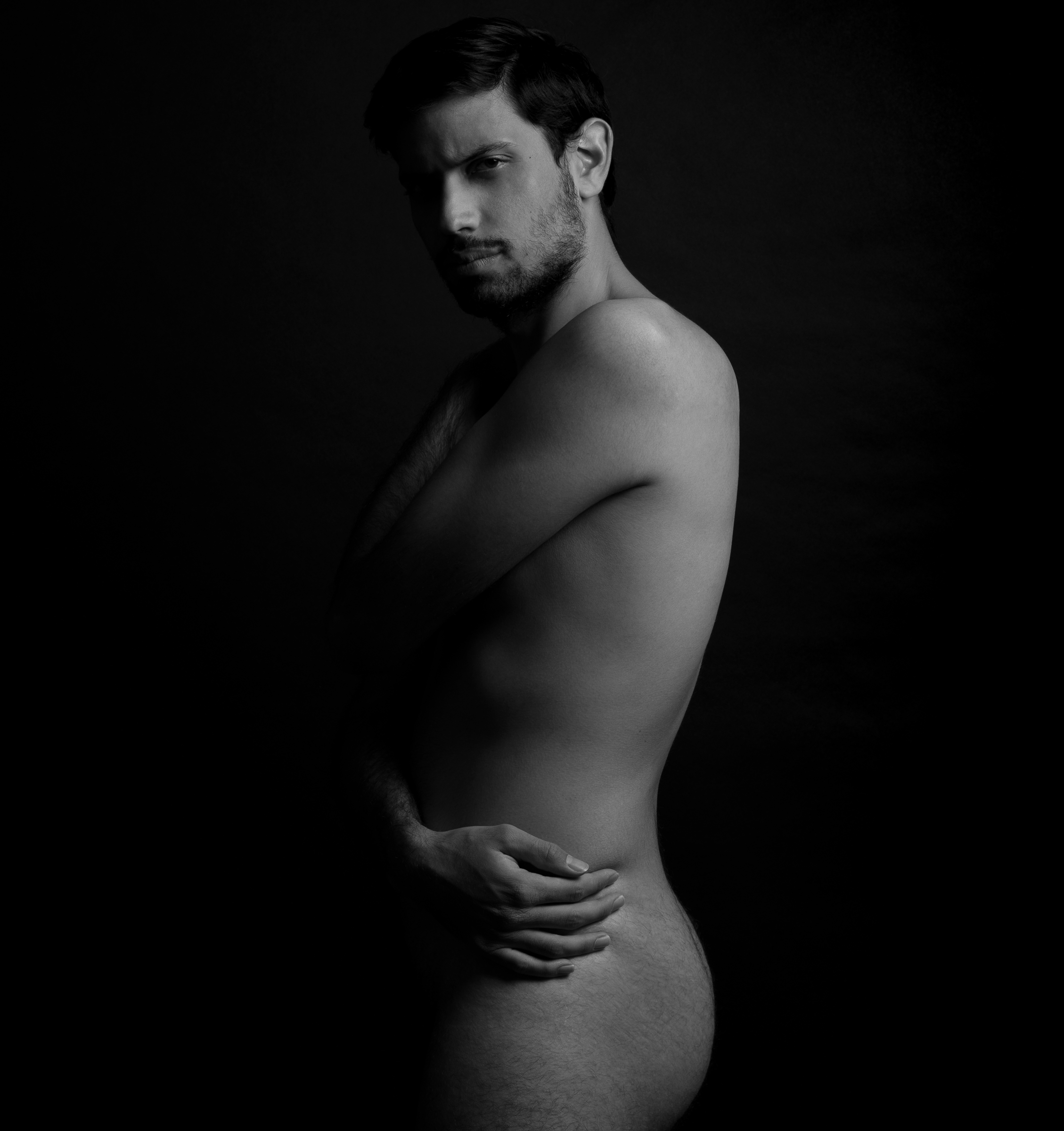 Une photo d'un homme nu qui s'enlace en noir et blanc