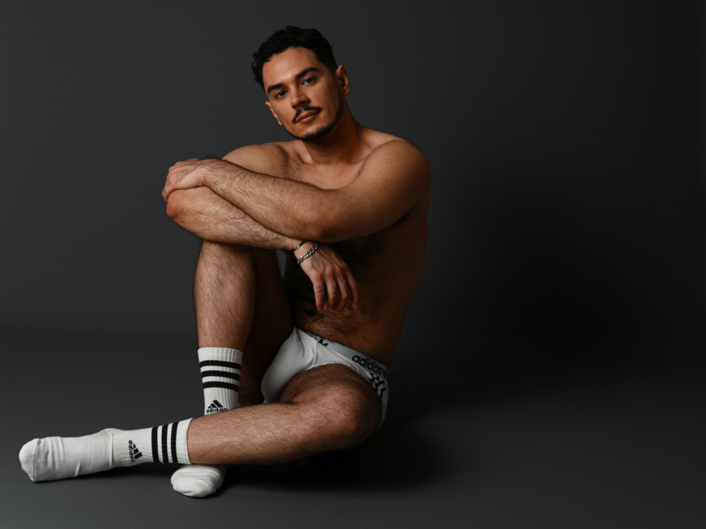Un homme musclé en boxer et chaussettes assis au sol dans un studio photo